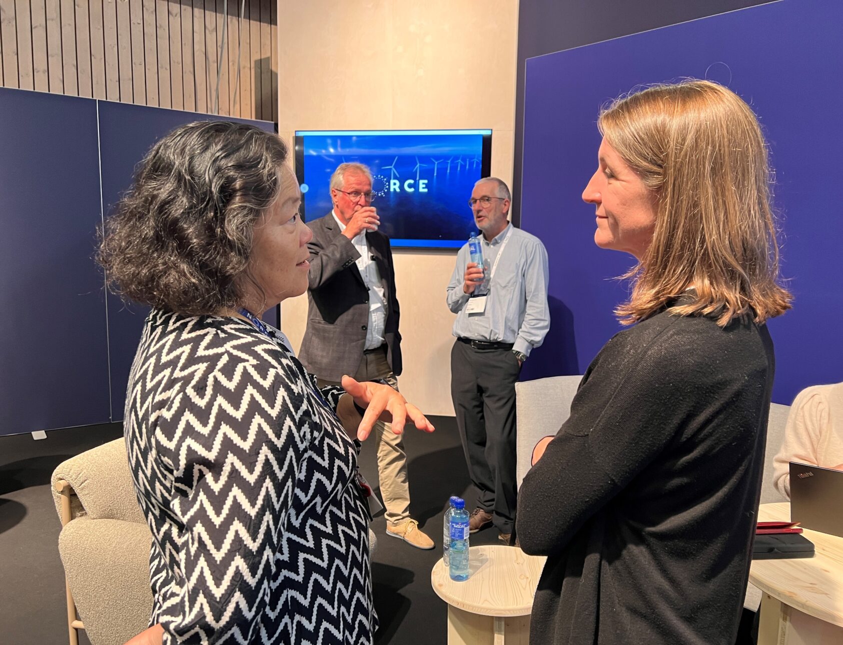 , Visit our stand for a chat! Here you see (from left) Ying Guo, Thor Arne Håverstad, Peter Breuhaus and Sarah Gasda, at our stand in 2022., ONS 2022, <p>NORCE</p>, Two women ina conversation, two men in the background.