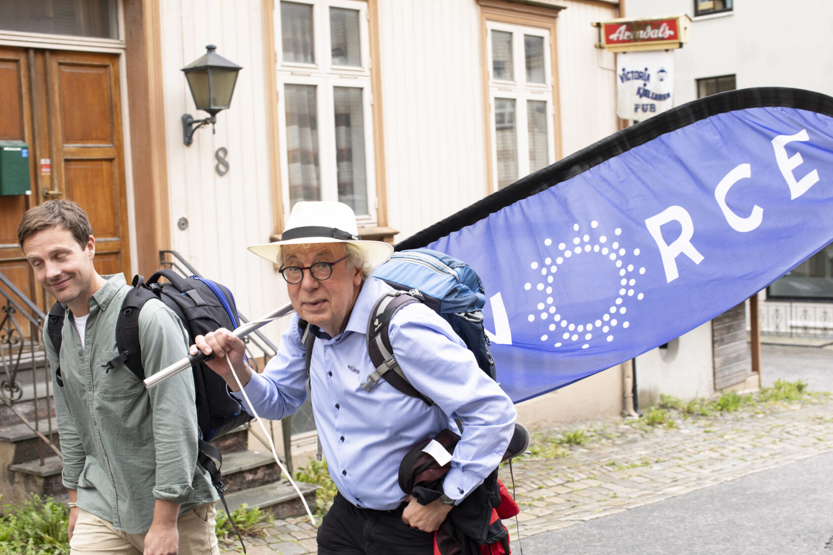 Rune Rolvsjord, NORCE, , 0 S0 A1861, , To menn går gjennom gaten, den ene med beachflag på ryggen