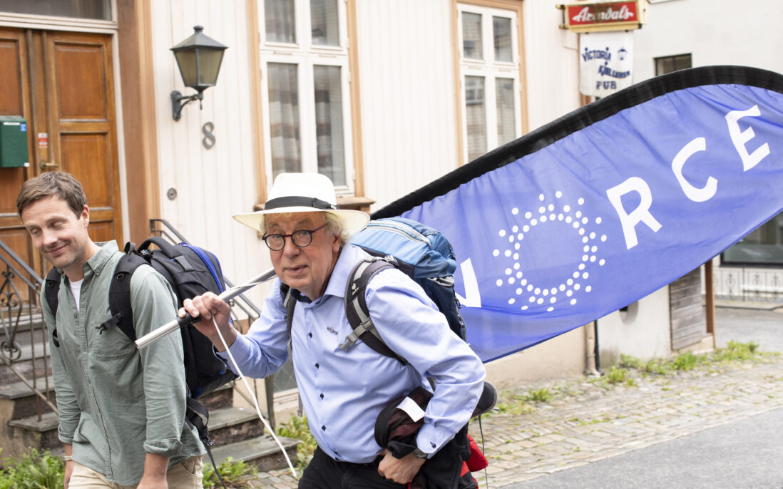 To menn går gjennom gaten, den ene med beachflag på ryggen