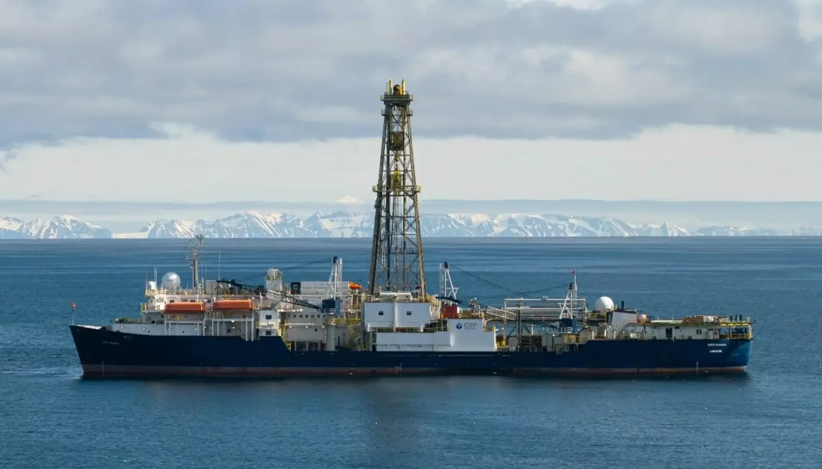 Foto: Chris Lyons, Slingshot Pictures, Boreskipet JOIDES Resolution vest for Spitsbergen., Joides Resolution Chris Lyons Slingshot Pictures, <p>Foto: Chris Lyons, Slingshot Pictures</p>, Skip på fjorden med boretårn, snødekte fjell i bakgrunnen