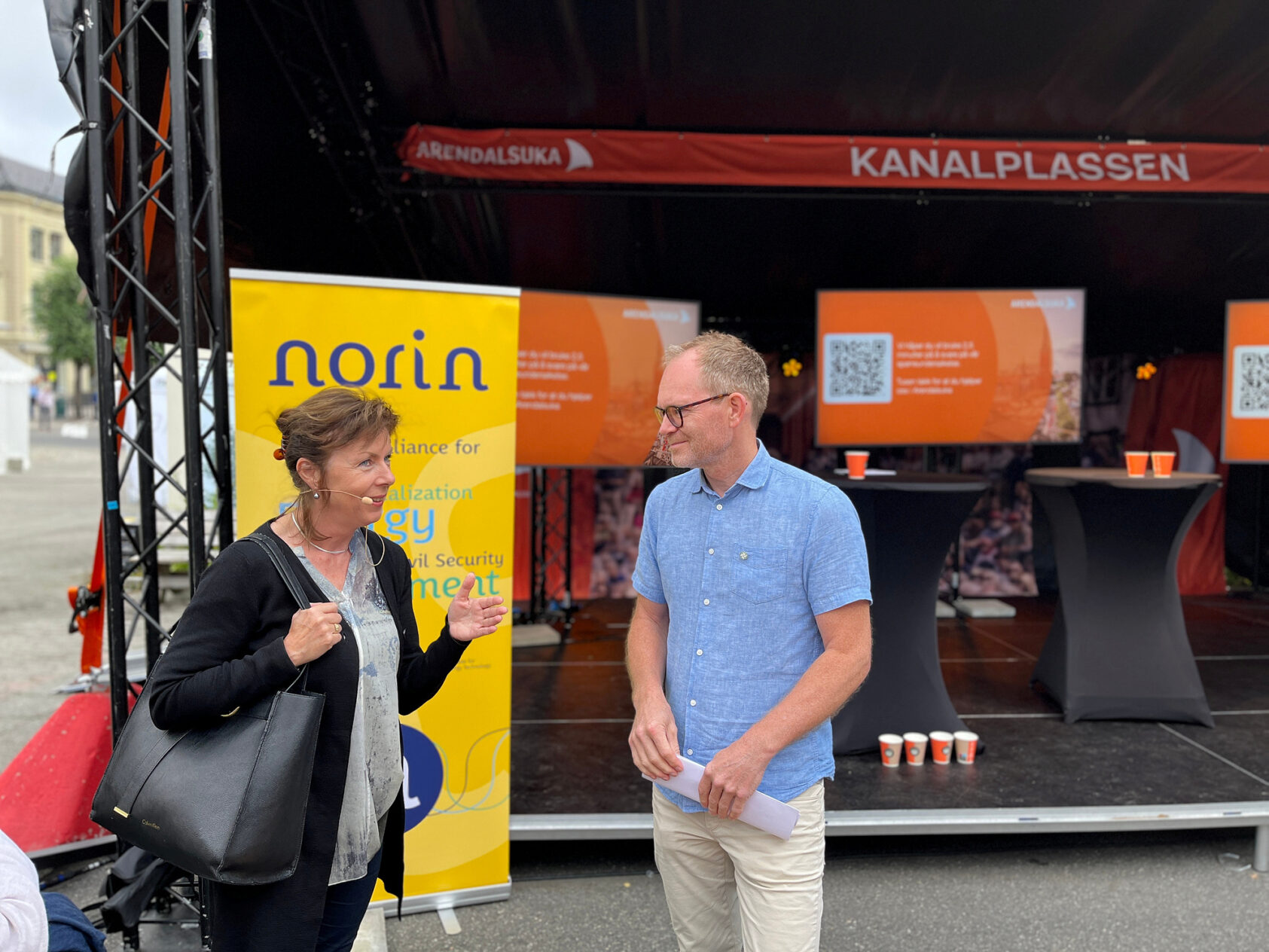 Rune Rolvsjord, Avdelingsleder Energi, ass. konserndirektør Energi og teknologi, Aina Berg fotografert under Arendalsuka i fjor. Her i passiar med Oddmund Hoel som ble kunnskaps- og høyere utdanningsminister i januar i år etter at Sandra Borch måtte gå av etter masteroppgaveskandale., IMG 8967, <p>Rune Rolvsjord, NORCE</p>, Kvinne og mann i samtale, en utendørscene i bakgrunnen.
