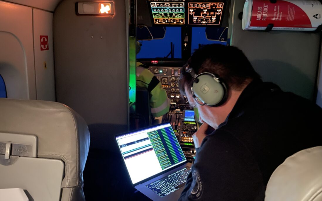 Mann med headset ser på dataskjerm om bord på fly